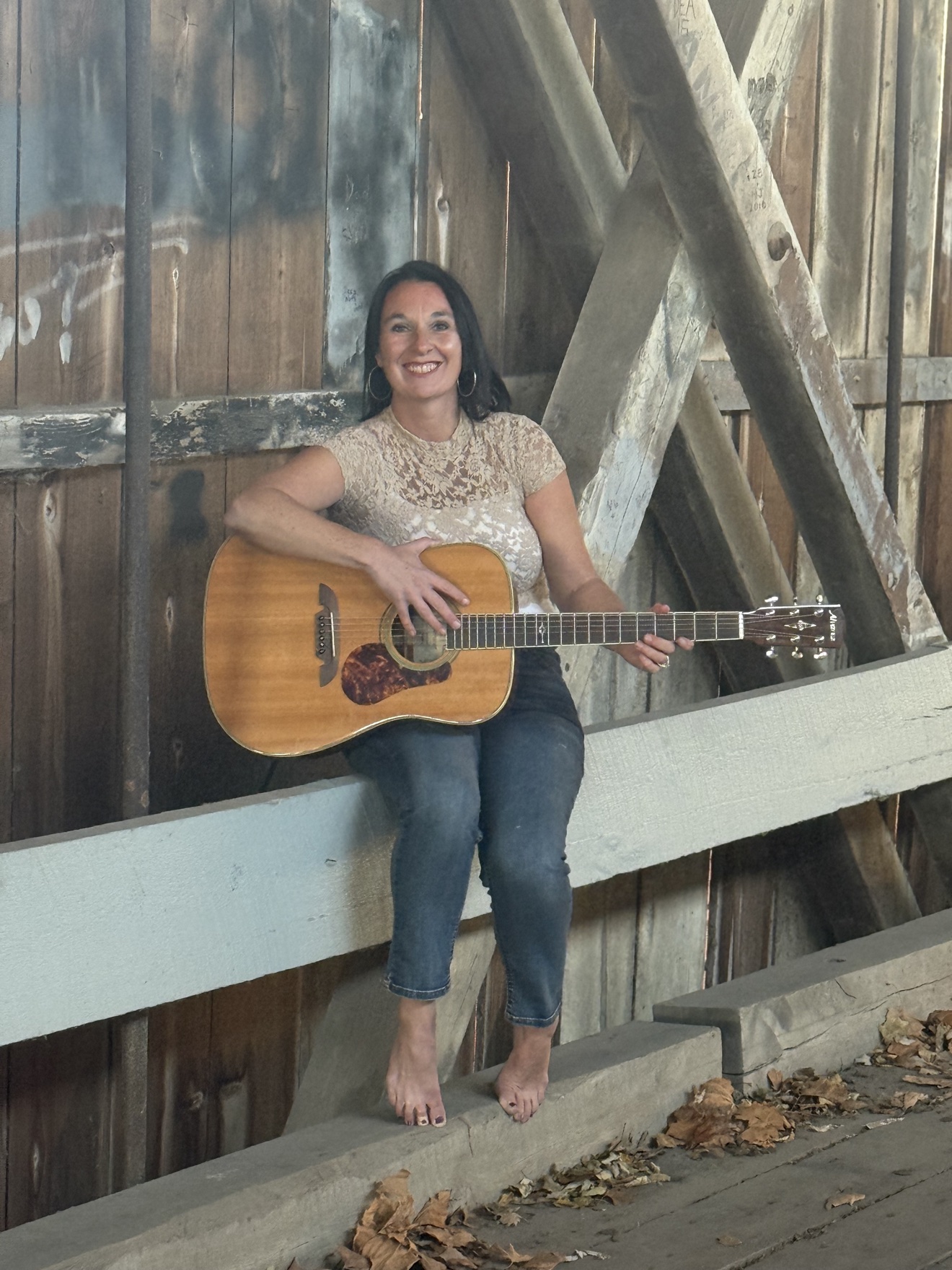 Angie Marquardt with her guitar at a covered bridge