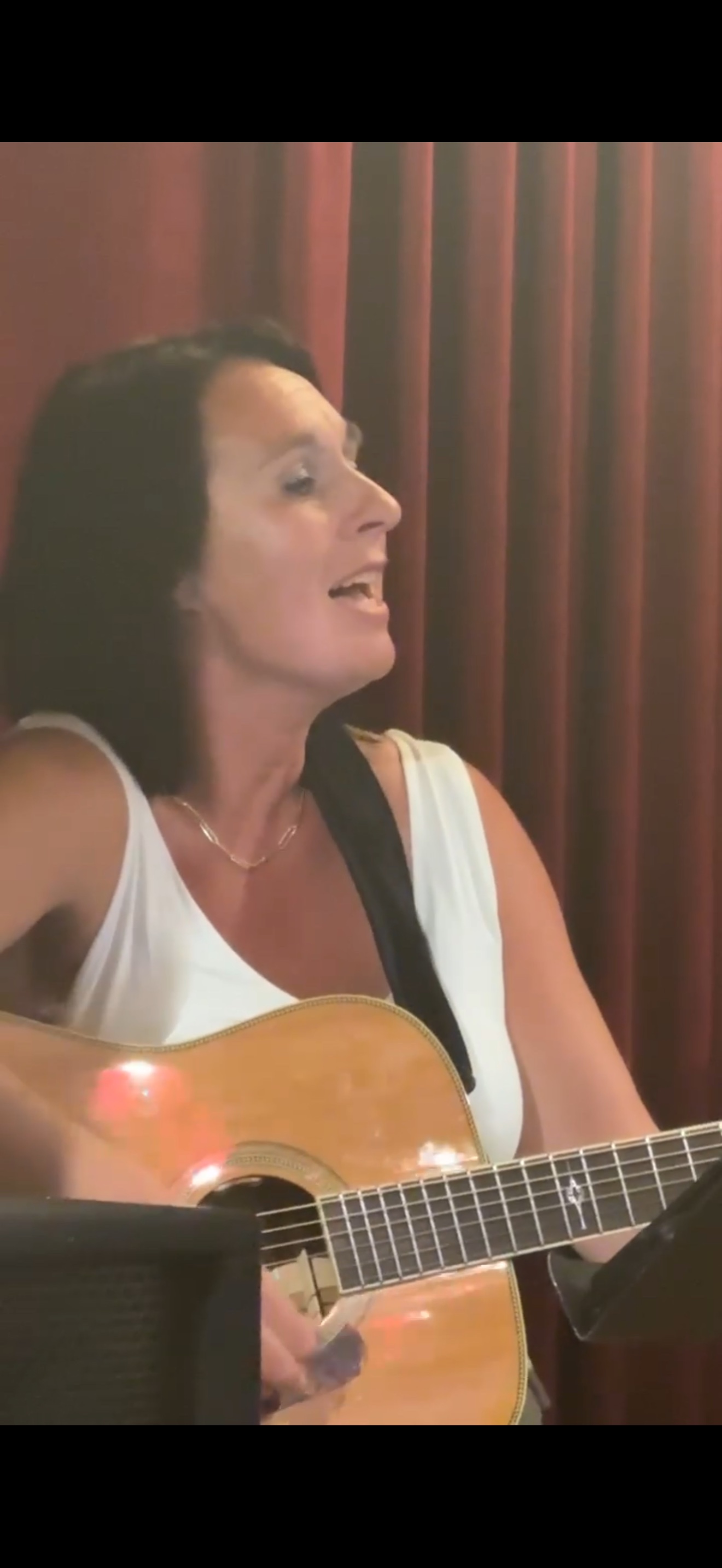 Angie Marquardt singing on stage in front of a red curtain